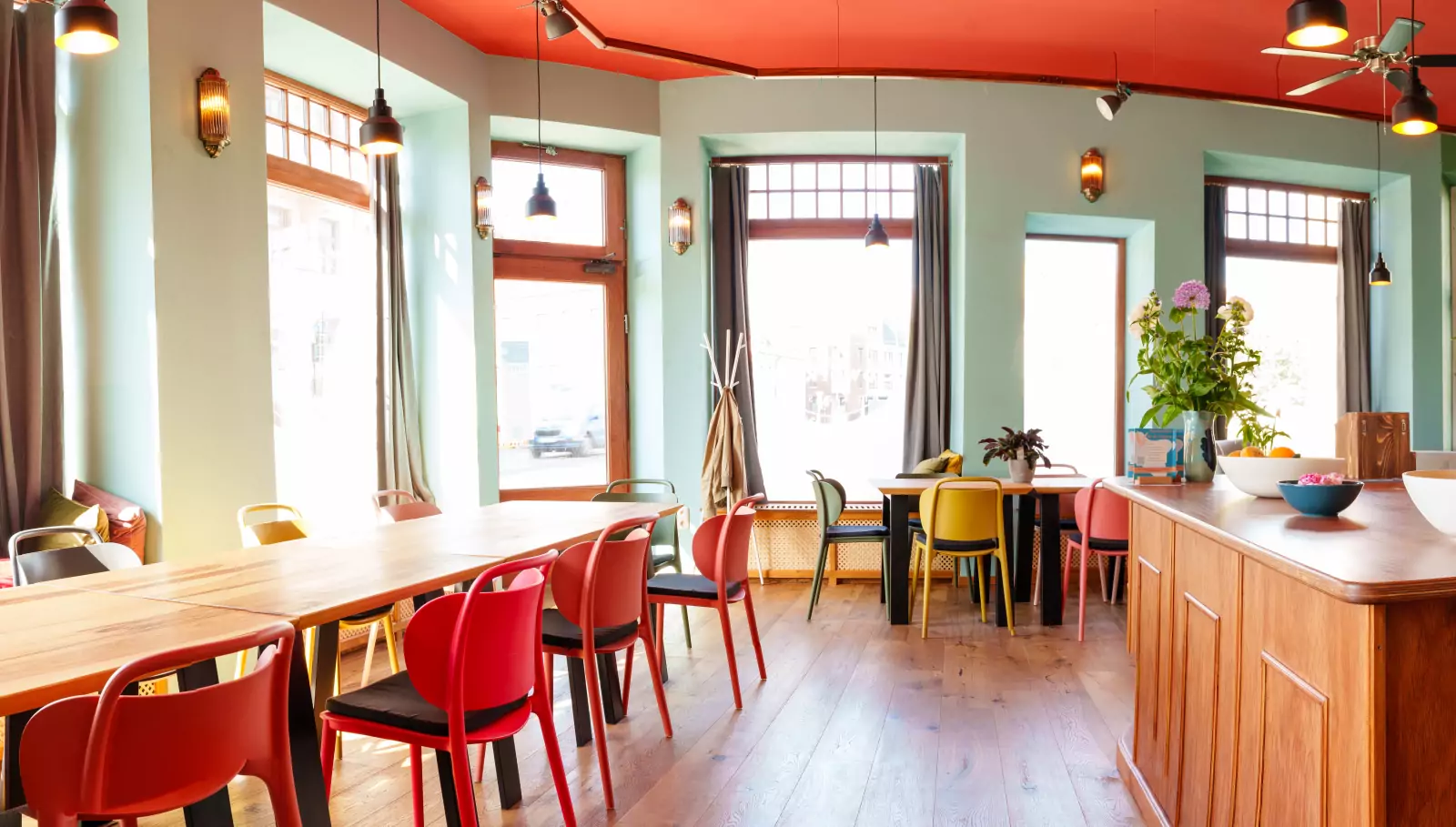 Interior view of the coworking space with long wooden tables and colorful chairs